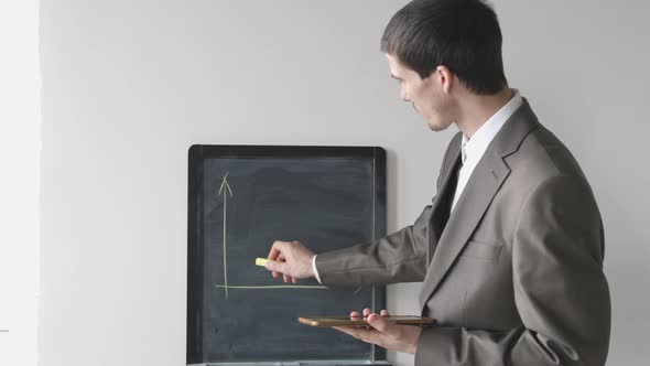 Creative Young Businessman in Suit Draws Chalk on Board