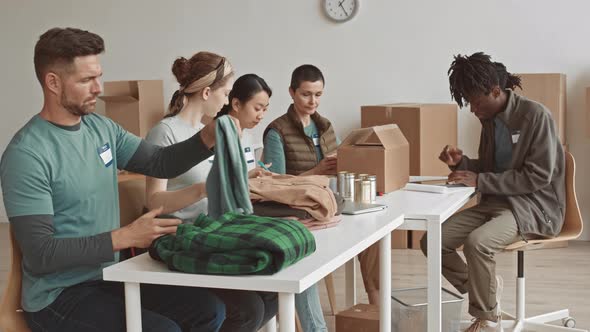 Volunteers Packing Charity Boxes with Clothes and Tins alt