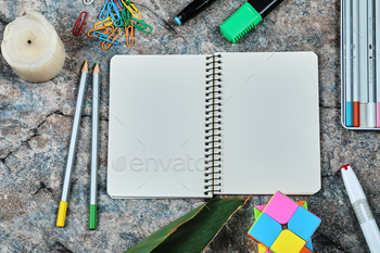 Empty notebook with pencils, candle, paper clips on the marble background