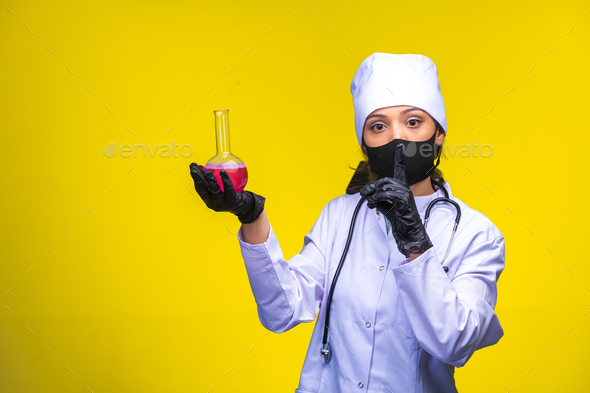 Isolated nurse in hand and face mask holds chemical flask and makes point to danger