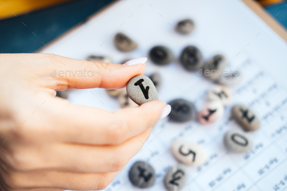 Woman numerologist hand with pebble stone with number one 1. Numerology Numbers Concept.