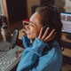 Young African American anchorwoman with headphones sitting in front of a microphone on the radio - PhotoDune Item for Sale