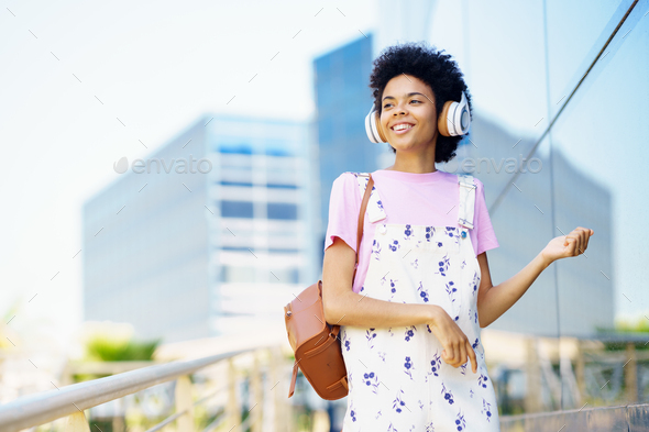 Content black woman listening to music in city