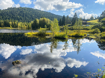 Beautiful clouds reflection in water of Lispach lake in the La Bresse, Vosges
