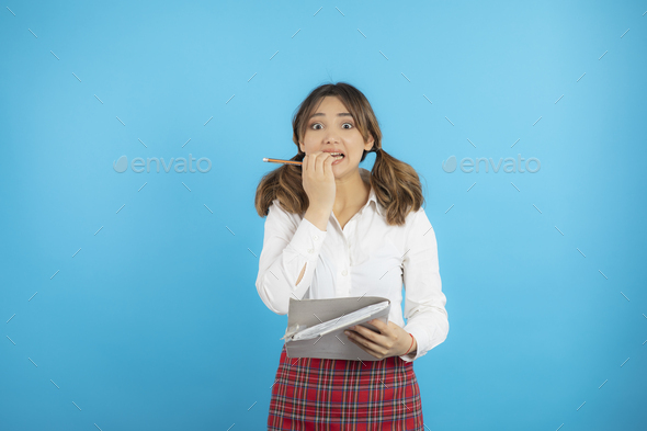 Scared girl can\'t make her home works and biting her nails.