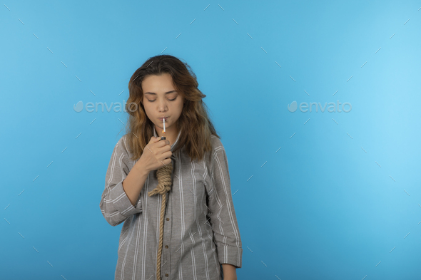 Exhausted young girl hang a rope around her neck and smoking.