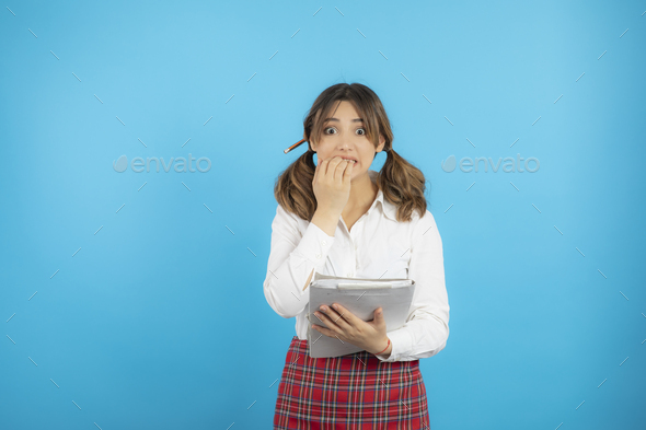 Scared college girl holding her notes and don\'t know what to do.