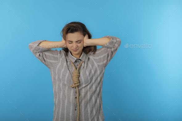 A stressed young adult hang a rope around her neck and put hands to her ear