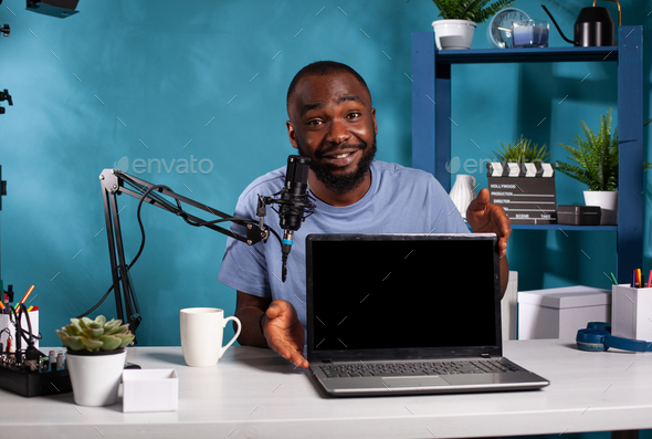 Portrait of vlogger presenting new model laptop on desk for video blog ...