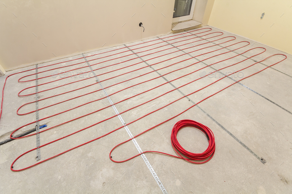 Heating red electrical cable wire roll on cement floor copy space background. Renovation and