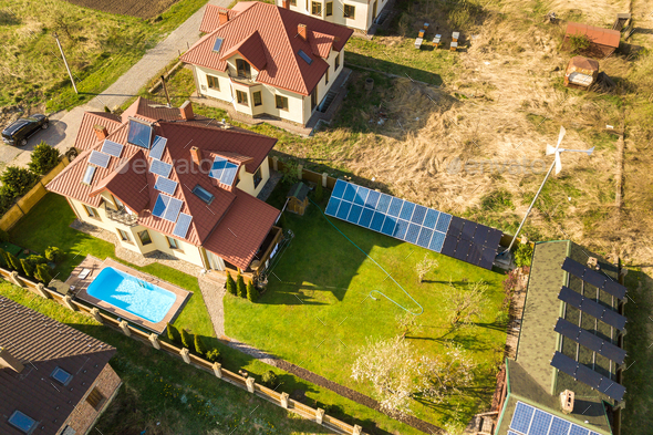 Aerial view of a private house with green grass covered yard, solar panels on roof, swimming pool
