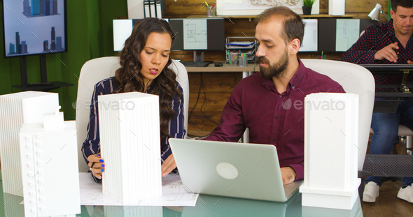 Architect and designer working on blueprints in creative media agency