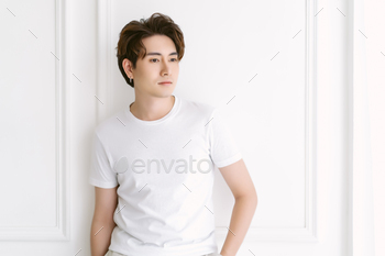 Attractive fashionable Asian man with earring, casual white t-shirt and standing.