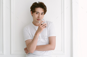 Attractive young Asian man wearing casual clothes relaxing drinking coffee standing leaning at wall
