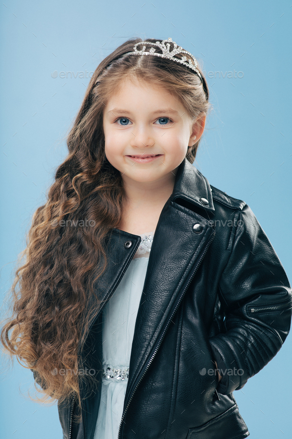 Vertical shot of attractive small female child has long curly hair ...