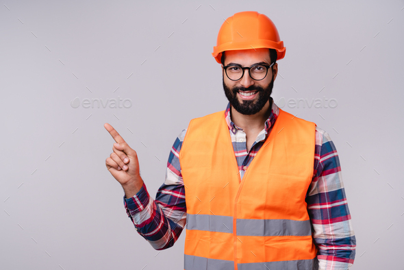 Cheerful Arab Builder In Hardhat And Uniform Pointing At Copy Space 