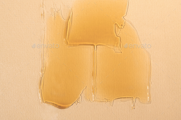 Orange color liquid cosmetic product applied with smears, face care cream on a beige background.