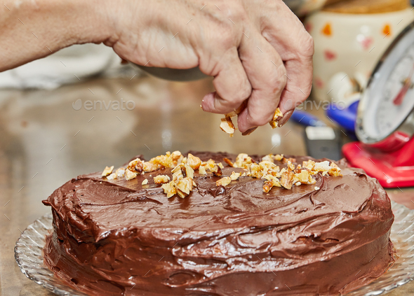 Chef sprinkles walnuts on the cake to make chocolate cake with pears and walnuts