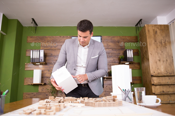 Young architect holding building model in conference room