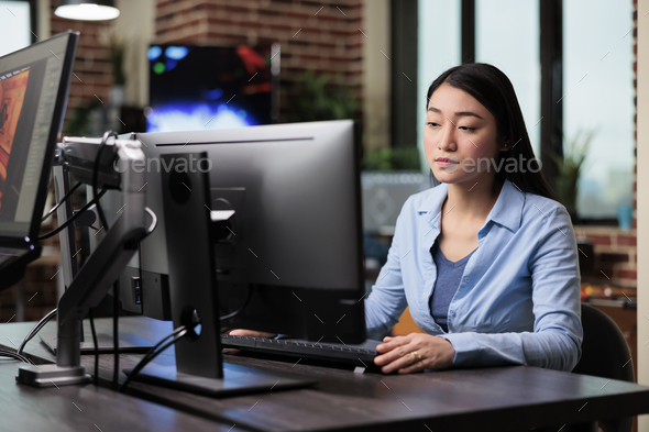 Beautiful asian creative artist sitting at desk while developing digital art