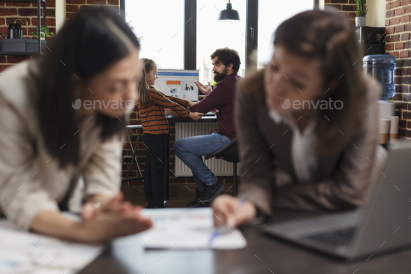 Businessperson daughter disturbing workplace colleague while women analyzing company paperwork.
