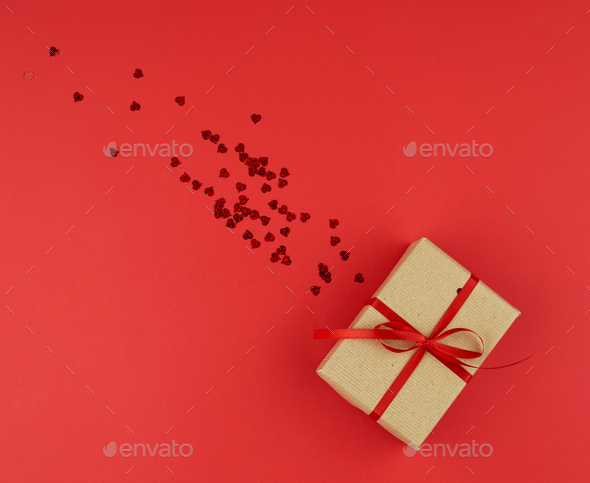 Female hand hold a box wrapped in red paper and tied with a red silk ribbon,  holiday Stock Photo by ndanko