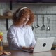 Redhead Smiling Young Woman with Curly Hair Putting on Headphones While Working at Laptop Computer - VideoHive Item for Sale