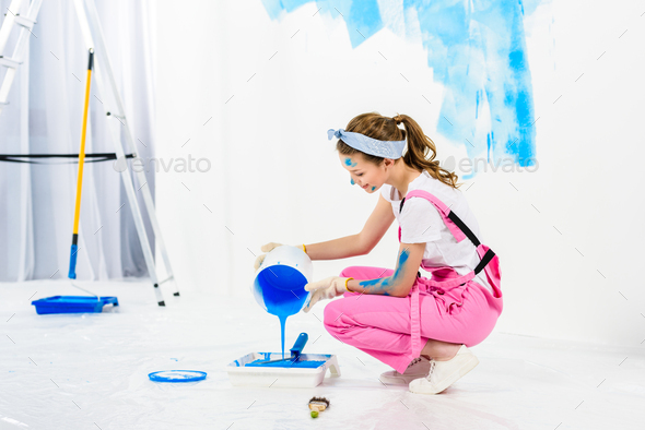 girl pouring paint from bucket into plastic paint tray