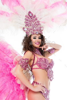 smiling woman posing in carnival costume with pink feathers and gems, isolated on white