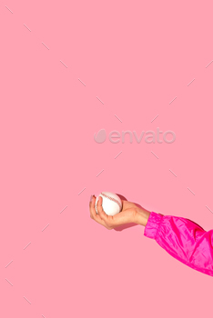 Cropped image of girl hand with baseball ball in hand on pink background