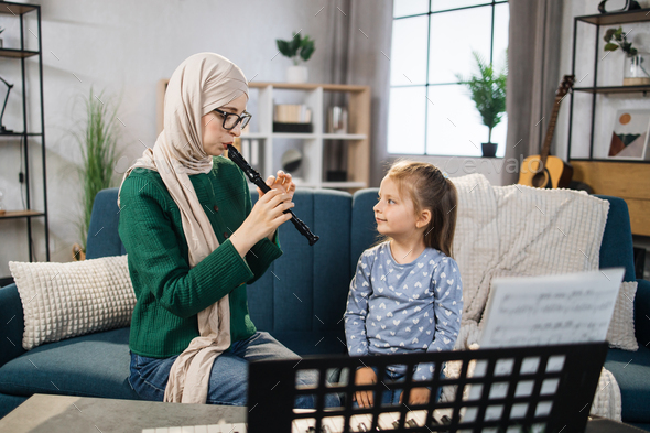 Muslim mom and little happy girl in music therapy by playing flute on music room.