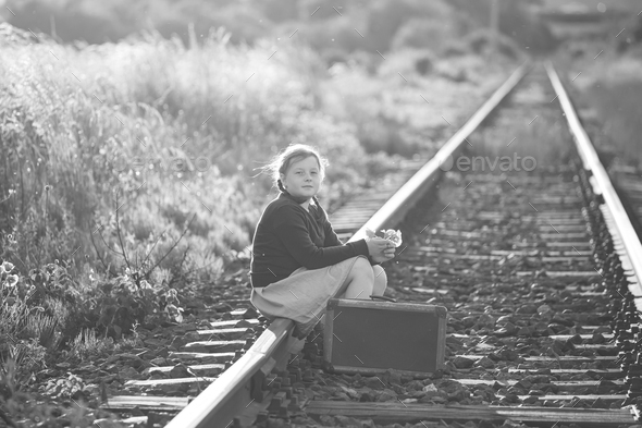 A little girl in a dress sits on an abandoned railroad tracks Stock ...