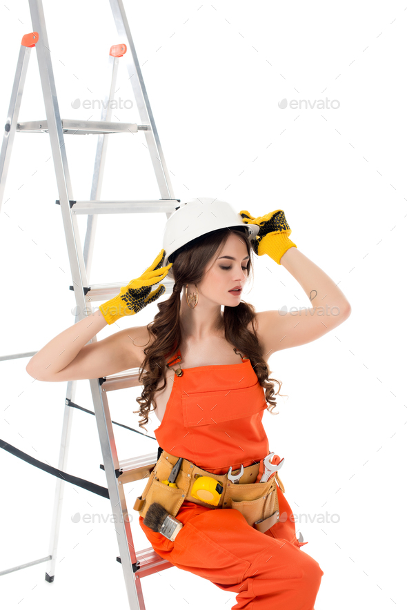 Brunette Workwoman In Overalls And Safety Helmet Posing Near Ladder 