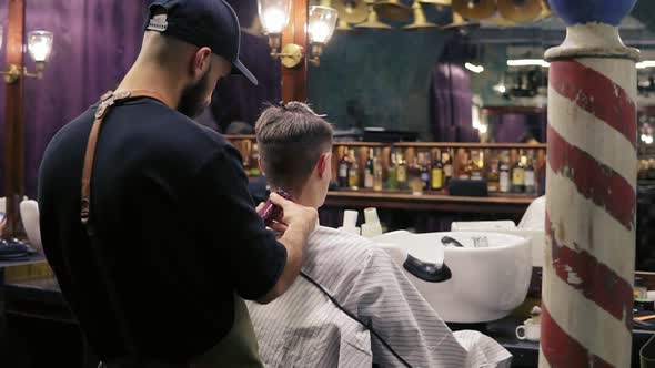 Back View of a Young Hairdresser Cutting Hair Using Electric Trimmer on the Neck of His Customer in alt