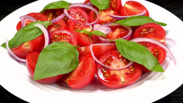 Tomato Salad with Basil and Chopped Onion in White Ceramic Dish Rotate Slowly alt