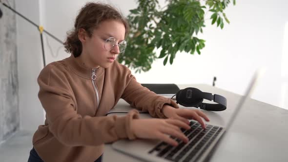Closeup Shot of a Serious Teen Girl Thoughtfully Looking to a Laptop Screen and Typing alt