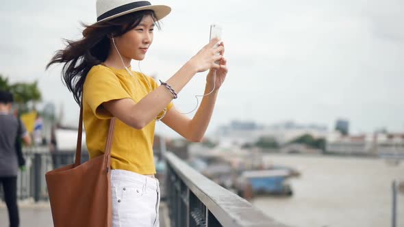 Young Asian woman using smartphones take photos around the Chao Phraya River.