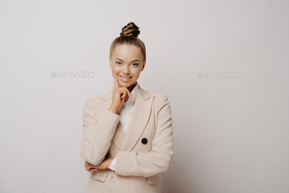 Professional attractive business lady keeps hand under chin