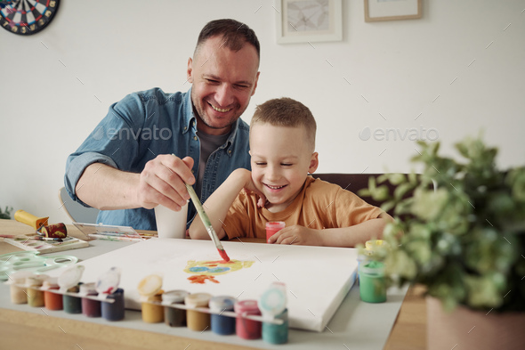 Kid boy and dad painting together