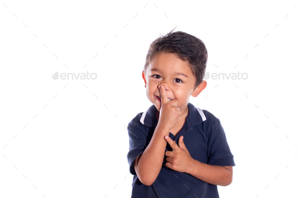 Embarrassed boy trying to pick his nose. Latin child laughing while touching tip of his nose.