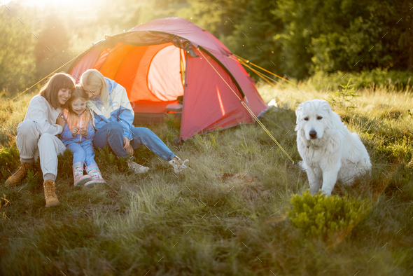 Two women sit with a little girl at campsite Stock Photo by RossHelen