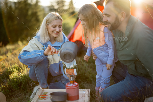 Couple with little girl cooking dried-food for hiking at campsite Stock ...