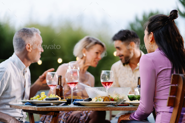 Friends having gossip conversation telling secret during summer dinner outdors