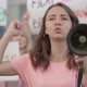 Young Female Eco-activist Yelling Through Megaphone with Crowd of People at the Background. Group of - VideoHive Item for Sale