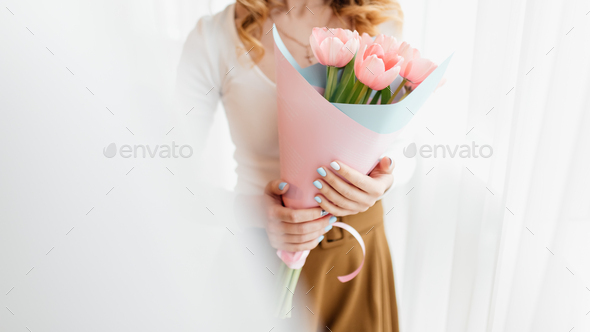 Young woman at home mother\'s day concept holding tulips bouquet smiling close up.
