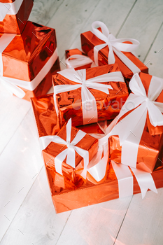 Group of red gift boxes with white ribbons on the floor.