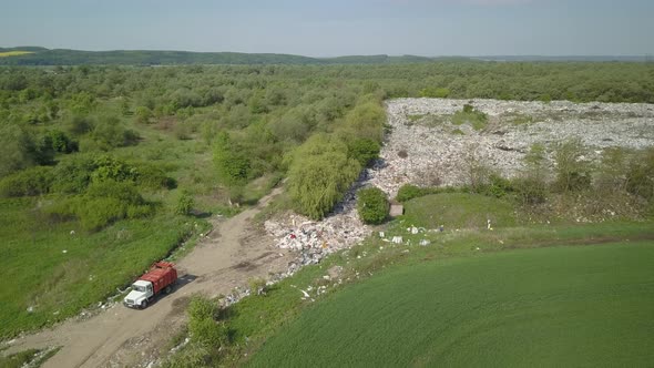 A Garbage Truck Arrives at a Natural Landfill. People Dump Waste at the Entrance. Aerial Video.