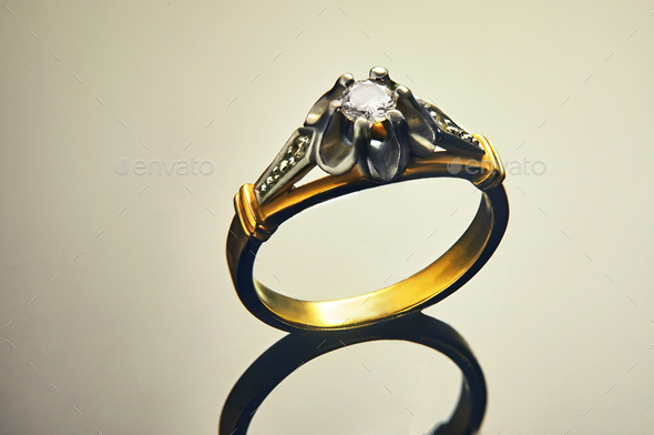 Gold ring in white and yellow gold with diamonds on a background with a gradient and reflection