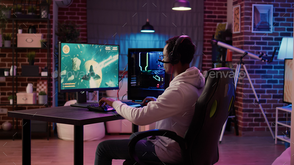 African american man playing fast paced multiplayer space shooter using pc gaming setup