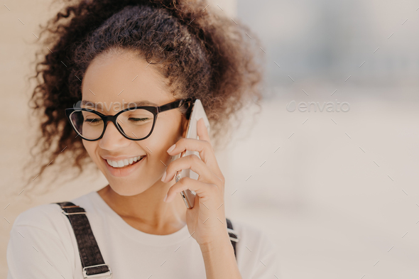 Close up portrait of cheerful woman with crisp hair, satisfied with tariffs for telephone call - Stock Photo - Images
